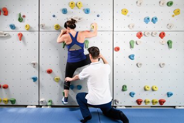 Gesundheitszentrum Therapeut mit Patientin an Kletterwand | © SalzburgerLand Tourismus/Marktl