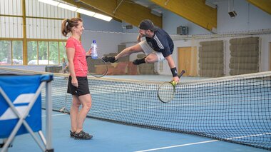 Una coppia gioca a tennis nella sala da tennis dell'Hotel Palace. | © Hotel Palace